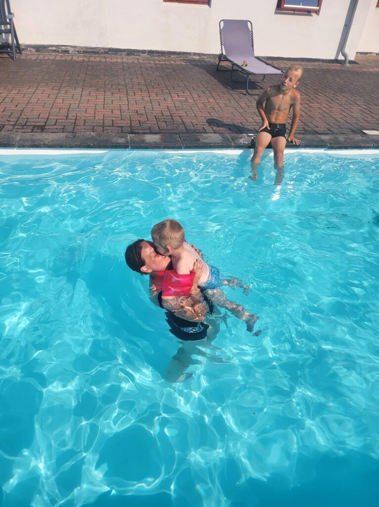 Familie nyder en solrig dag i swimmingpoolen